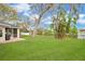 Expansive backyard featuring lush lawn, mature trees, lake view, and screened patio, perfect for outdoor entertaining at 1837 Farrington Dr, Lakeland, FL 33809