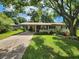 Inviting single-story home with a covered carport, green lawn and a beautiful mature shade tree at 220 Pinehurst Dr, Auburndale, FL 33823