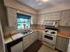 Functional kitchen featuring a sink with a window above it and white appliances at 220 Pinehurst Dr, Auburndale, FL 33823