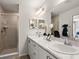 Well-lit bathroom featuring double sinks, marble countertops, and tiled shower with glass door at 230 Turtle Bay Ave, Winter Haven, FL 33881