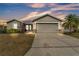 Charming single-story home with a well-manicured lawn, gray exterior and a two-car garage in a residential neighborhood at 2700 Oak Hammock Loop, Mulberry, FL 33860