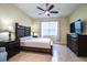 Comfortable bedroom with a large bed, two dressers, a ceiling fan, curtains, and tile flooring at 297 Spirit Landings Cir, Winter Haven, FL 33880