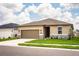 Charming single-story home with a two-car garage, tan stucco siding, stone accents, and manicured front lawn at 297 Spirit Landings Cir, Winter Haven, FL 33880