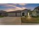Charming single-story home boasts a 2-car garage, well-maintained lawn, and inviting entryway with a beautiful sky at sunset at 2991 Flying Blackbird Rd, Bartow, FL 33830