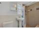 Cozy bathroom features a tiled shower, pedestal sink, toilet, and a mirrored cabinet at 317 S 8Th St, Haines City, FL 33844