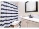 A compact bathroom is equipped with a shower featuring a striped curtain, a toilet, and a vanity at 3281 Enclave Blvd, Mulberry, FL 33860