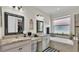 Bright bathroom featuring double granite sinks, framed mirrors, a large window, and a soaking tub at 3926 Aquilla Dr, Lakeland, FL 33810