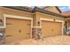 Tan home featuring garage doors accented by stone pillars and decorative hardware at 3926 Aquilla Dr, Lakeland, FL 33810