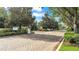 Community entrance with gatehouse, mature trees, and manicured landscaping under a sunny blue sky at 4088 Prima Lago Cir, Lakeland, FL 33810