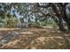 A long view of the front exterior shows the sunroom and the large tree creating shade in the yard at 415 Manor Dr, Bartow, FL 33830