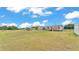 Far off exterior view of a single story home with two sheds and a large open green lawn at 4207 Ollie Rd, Lakeland, FL 33810