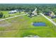 Aerial view of a property with a pond and fenced pasture, surrounded by lush greenery and neighboring homes at 4404 Musket Dr, Lakeland, FL 33810