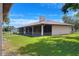 View of home's screened lanai, metal roof, stucco siding, and spacious lawn on a sunny day at 4404 Musket Dr, Lakeland, FL 33810