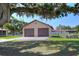 Detached garage with dual doors, set against lush greenery, with a well-maintained lawn and landscaping at 4404 Musket Dr, Lakeland, FL 33810