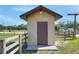 Exterior of tan outbuilding with dark brown door and fenced yard at 4404 Musket Dr, Lakeland, FL 33810