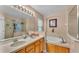 Bright bathroom with double sinks, a large mirror, soaking tub, and glass shower at 506 Henley Cir, Davenport, FL 33896