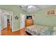 A bedroom with wood floors, a ceiling fan, dresser, and open doorways to a bathroom and living room at 506 Henley Cir, Davenport, FL 33896