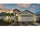 Inviting home exterior at dusk featuring a two-car garage, lush landscaping, and warm lighting at 506 Henley Cir, Davenport, FL 33896