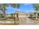 Charming single-story home with a well-manicured lawn, palm trees, and attached two-car garage at 506 Henley Cir, Davenport, FL 33896