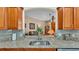 Kitchen sink view showcasing granite countertops, wood cabinets, and connection to the living room at 506 Henley Cir, Davenport, FL 33896
