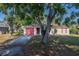 A charming single-story home with a red garage door, mature landscaping and a driveway at 526 Marklen Loop, Polk City, FL 33868
