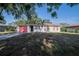 Charming single-story home with a red garage door, front lawn, and lovely landscaping at 526 Marklen Loop, Polk City, FL 33868