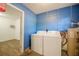 Bright laundry room with white washer and dryer, and a blue accent wall provides a convenient and functional space at 526 Marklen Loop, Polk City, FL 33868