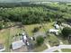 Aerial view of the property showing the home, outbuildings, green lawns, surrounding trees, and adjacent open fields at 5339 Meadow Grove Trl, Lakeland, FL 33810