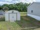 A white metal storage shed stands in the backyard on a grassy lawn, near the house and a chain link fence at 5339 Meadow Grove Trl, Lakeland, FL 33810