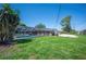 Backyard view showing in-ground screened-in pool and brick house surrounded by green grass and palm trees at 5604 Stratford Ln, Lakeland, FL 33813