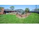Manicured backyard with brick home, an in-ground pool, mature palm trees and lush green lawn at 5604 Stratford Ln, Lakeland, FL 33813