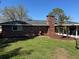The rear view of the exterior features a brick chimney, mature landscaping, and screened-in lanai at 5604 Stratford Ln, Lakeland, FL 33813