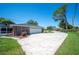 A brick home with a two-car garage and long driveway, surrounded by a green lawn and mature trees on a sunny day at 5604 Stratford Ln, Lakeland, FL 33813