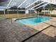 Backyard in-ground pool with a screened-in enclosure and a brick paver pool deck at 5604 Stratford Ln, Lakeland, FL 33813
