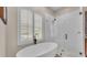 This bathroom features a standalone tub beneath shuttered windows and a frameless glass shower with decorative tiling at 6546 Eagle View Loop, Lakeland, FL 33813