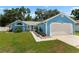 Charming blue home featuring a well-maintained lawn, two-car garage, and colorful landscaping at 6810 Palomino Dr, Lakeland, FL 33811