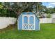 A charming blue shed with white trim, standing out in the well-maintained green backyard at 6810 Palomino Dr, Lakeland, FL 33811