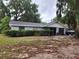 Cozy single-story home features a gray brick facade, dark roof, attached garage, and lush shrubbery at 930 E Tee Cir, Bartow, FL 33830