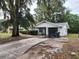 Charming single-story home with garage, gray brick, front shrubbery, and large front driveway at 930 E Tee Cir, Bartow, FL 33830