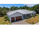 Aerial view of the house with a large garage, attractive landscaping, and a metal roof at 1 Brogden Se Ct, Winter Haven, FL 33880