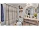 Well-lit bathroom featuring a shower with curtain, wood vanity, round mirror and wall shelves at 1215 Evergreen Park Cir, Lakeland, FL 33813
