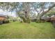 Expansive backyard featuring mature trees, lush green grass, and partial view of the home's exterior at 1317 Old Polk City Rd, Lakeland, FL 33809