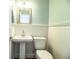 This white paneled bathroom features pedestal sink and toilet, illuminated by modern sconces at 1328 Edgewater Beach Dr, Lakeland, FL 33805