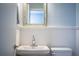 This white paneled bathroom features pedestal sink and toilet, illuminated by modern sconces at 1328 Edgewater Beach Dr, Lakeland, FL 33805
