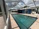 A crystal clear swimming pool inside an enclosed and screened patio with brick surround and a view of the lake at 1328 Edgewater Beach Dr, Lakeland, FL 33805