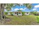 View of the rear of the home with a spacious yard, mature trees, and a covered patio area at 1507 Neptune Dr, Lakeland, FL 33801