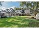 Expansive backyard with mature trees, a screened pool enclosure, and an inviting fire pit area; ideal for entertaining at 1516 Jae Pl, Lakeland, FL 33803