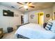 Neutral bedroom featuring a ceiling fan, mounted TV, and open access to the bathroom at 2040 Chickadee St, Bartow, FL 33830