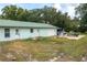 View of the rear exterior featuring a metal roof, large driveway, and parking for several vehicles at 2219 New Jersey Rd, Lakeland, FL 33803