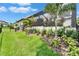 Well-manicured backyard with tropical landscaping, a screened-in patio, and steps leading to the home at 2662 Delphi Hills Ct, Lakeland, FL 33812